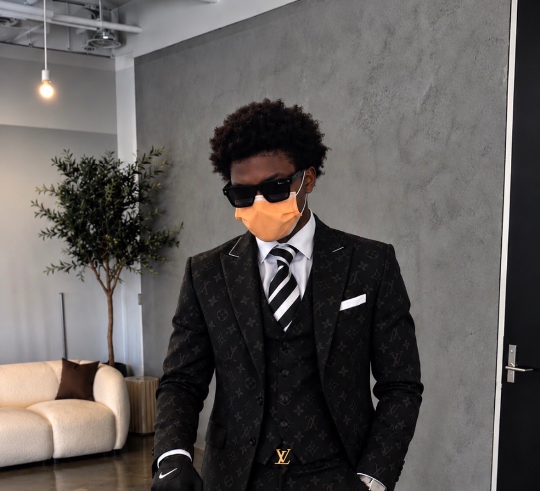 Ashton Clarke wearing a black Louis Vuitton suit in a modern living room